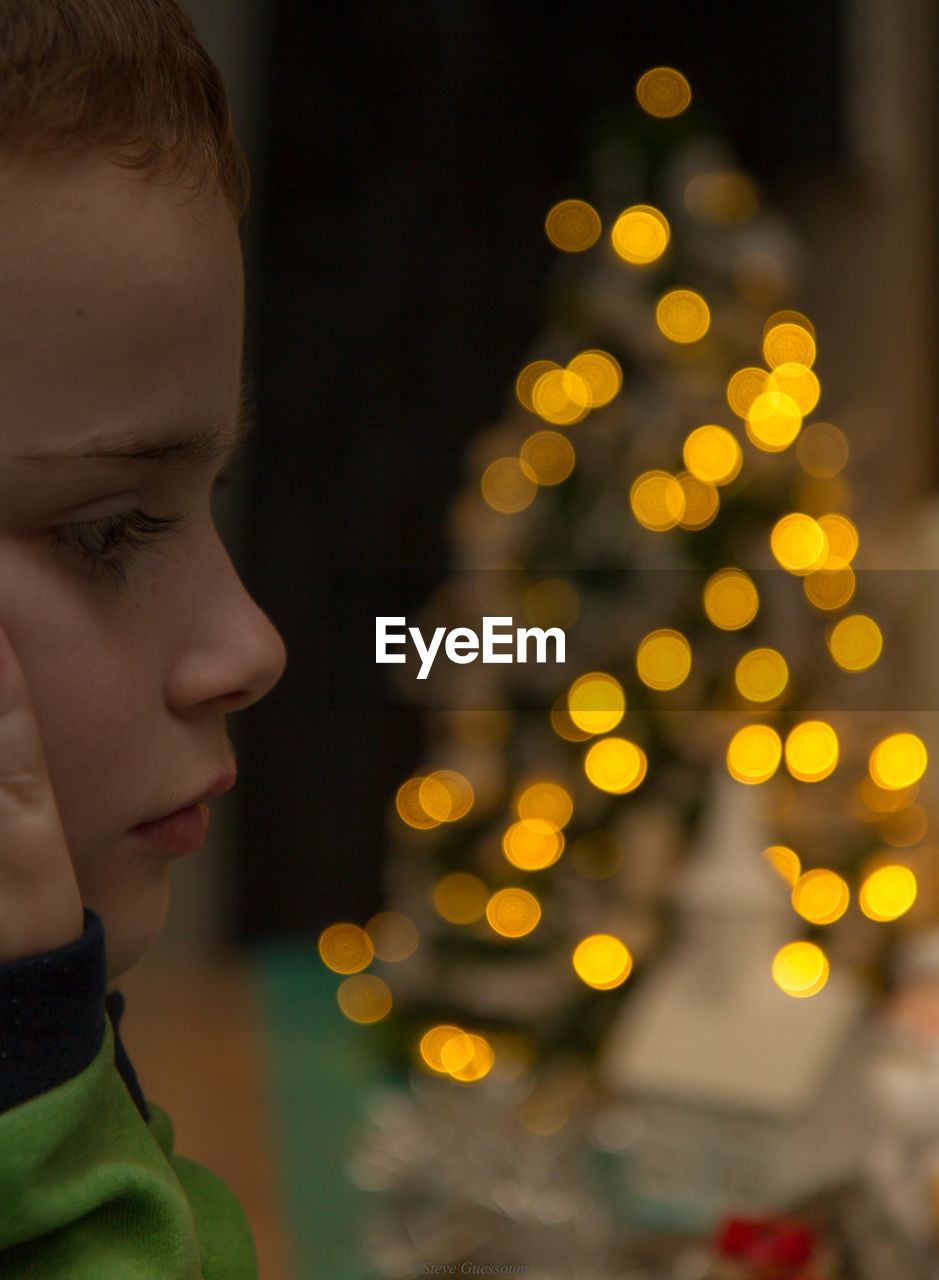 REAR VIEW OF BOY LOOKING AT ILLUMINATED CHRISTMAS TREE DURING FESTIVAL