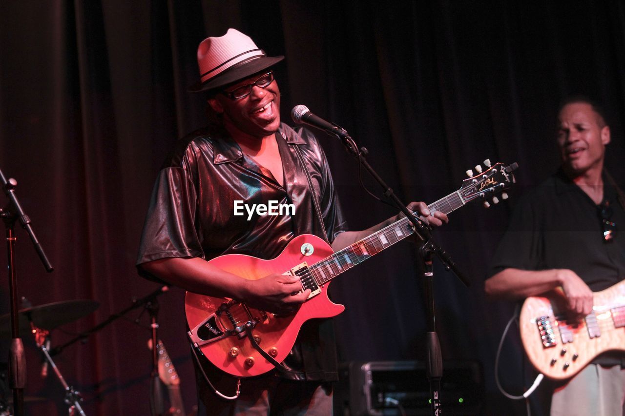 FULL LENGTH OF MAN PLAYING GUITAR AT CAMERA