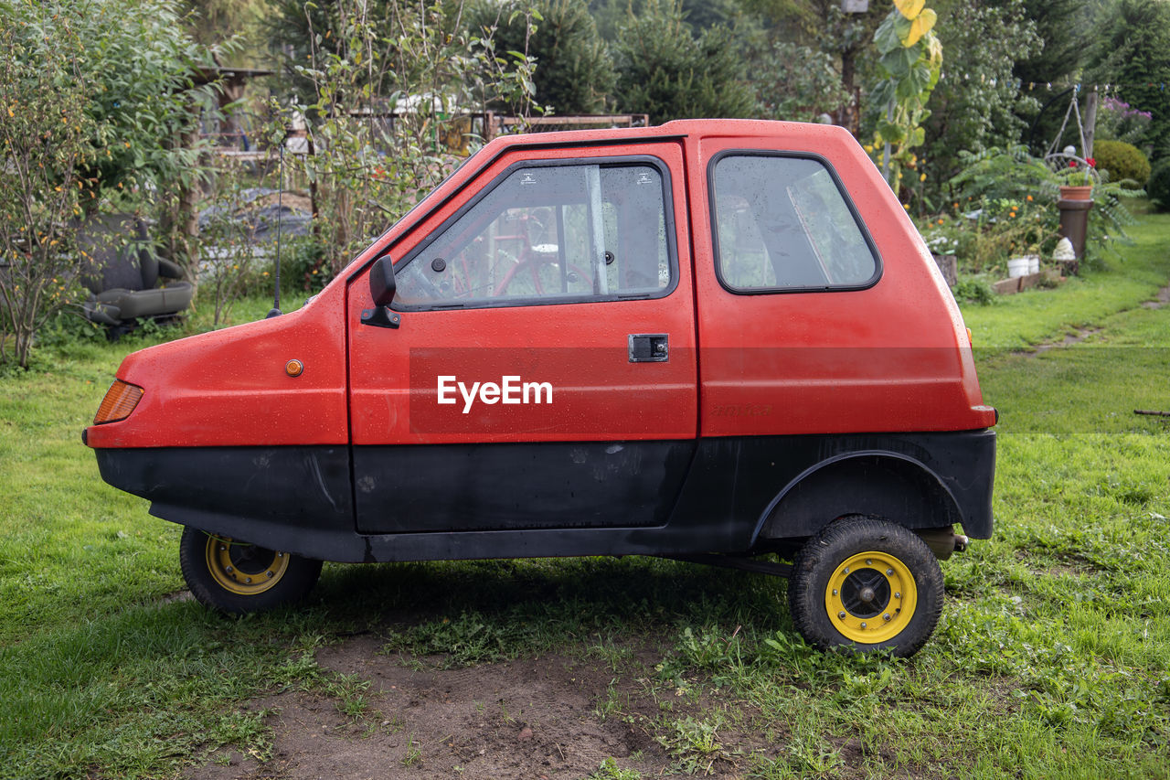 car, vehicle, land vehicle, mode of transportation, transportation, plant, tree, city car, motor vehicle, nature, red, day, grass, no people, land, light commercial vehicle, green, outdoors, microvan