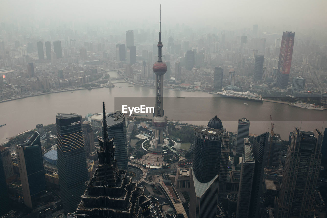 From above of river waterfront district of central shanghai with contemporary towers and buildings in dense smog