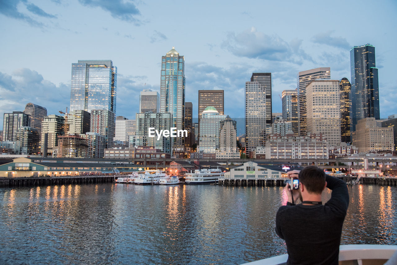 WOMAN PHOTOGRAPHING WITH CITYSCAPE IN BACKGROUND