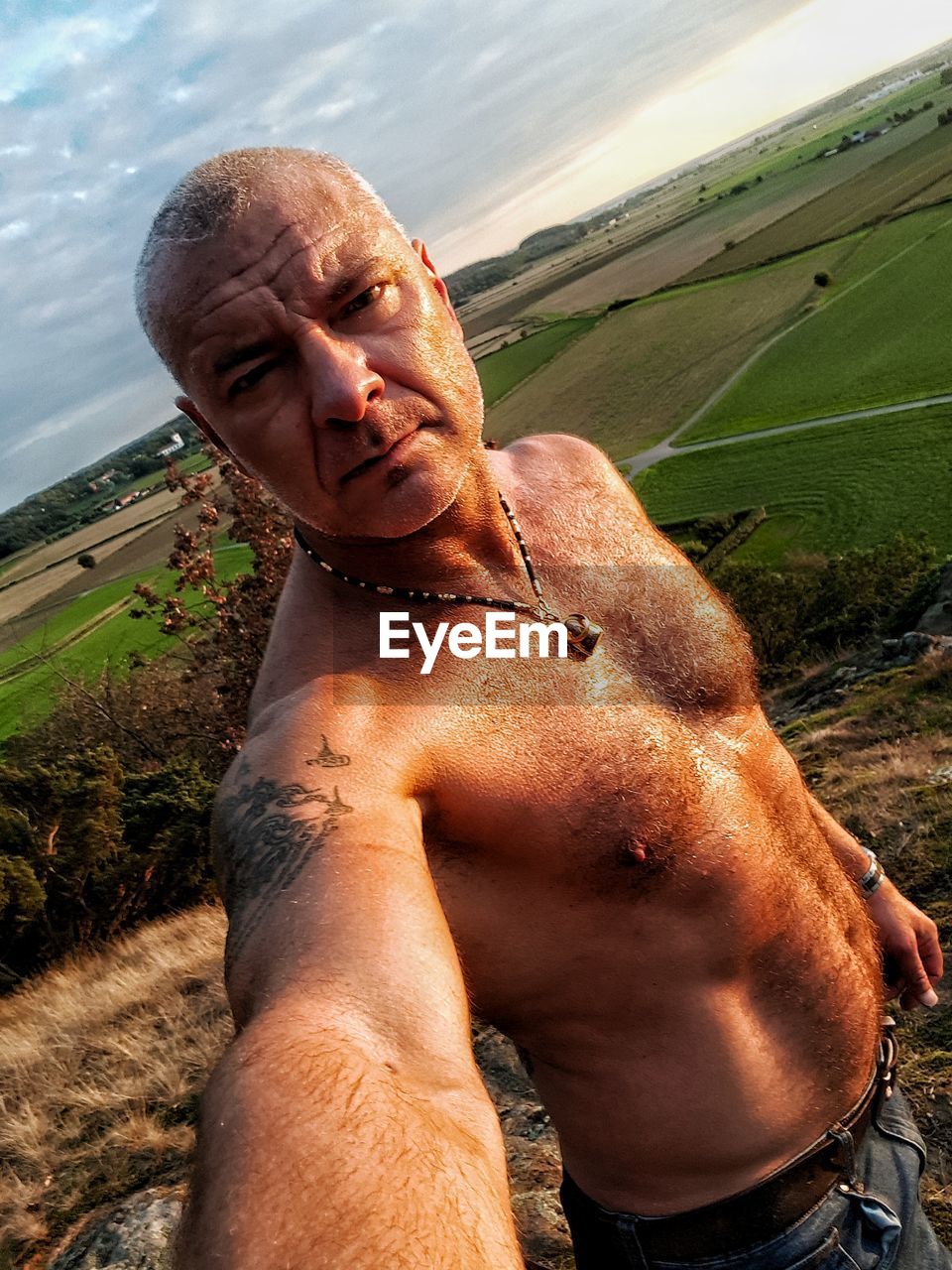 Portrait of shirtless man standing by landscape
