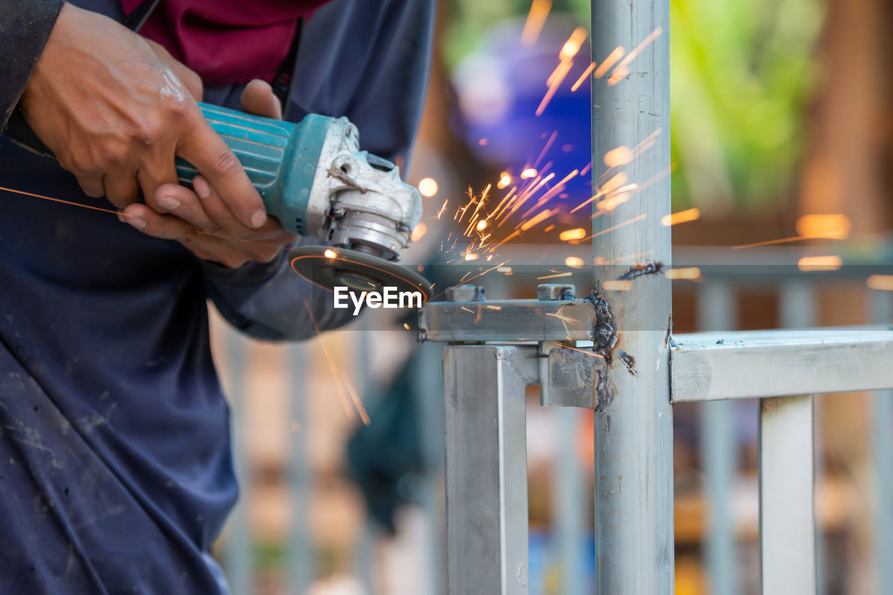 Midsection of man working on metal