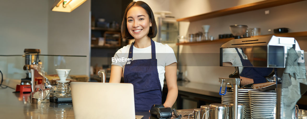 portrait of young woman using mobile phone while sitting in cafe