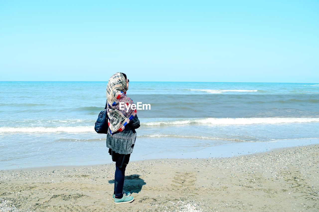 FULL LENGTH OF PERSON STANDING ON BEACH AGAINST SKY