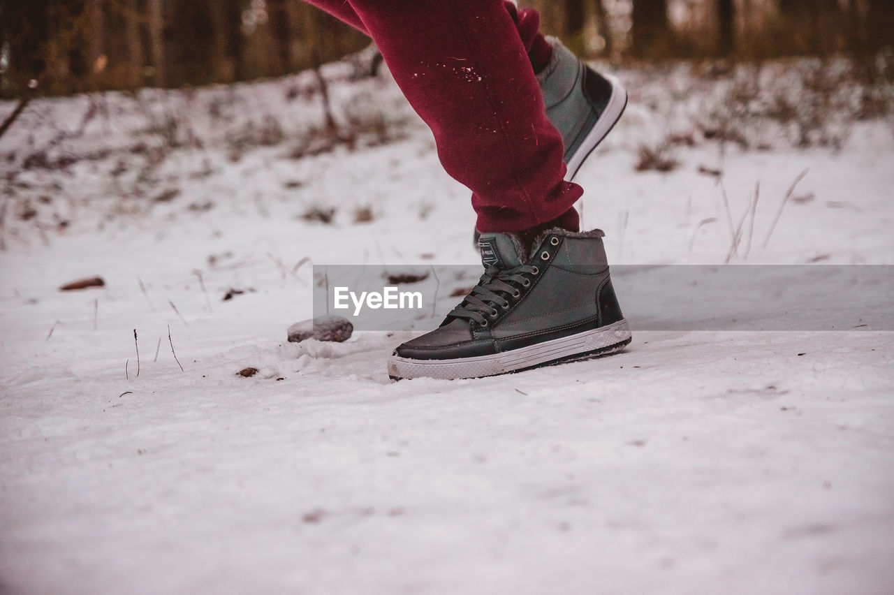winter, footwear, one person, low section, human leg, red, snow, cold temperature, shoe, limb, human limb, spring, white, nature, lifestyles, leisure activity, adult, sports, winter sports, selective focus, clothing, day, land, motion, outdoors, women, human foot, freezing, vitality, black, tree