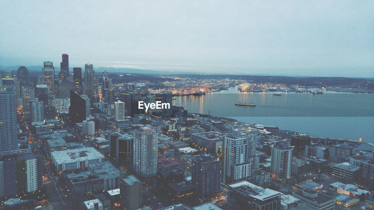 High angle view of cityscape by river against sky at dusk