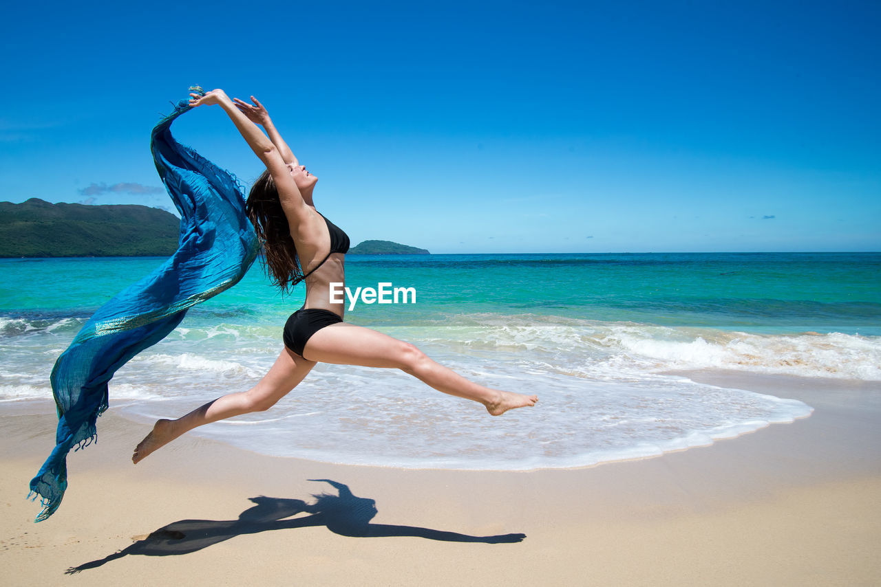 Girl dancing with scarf on beach