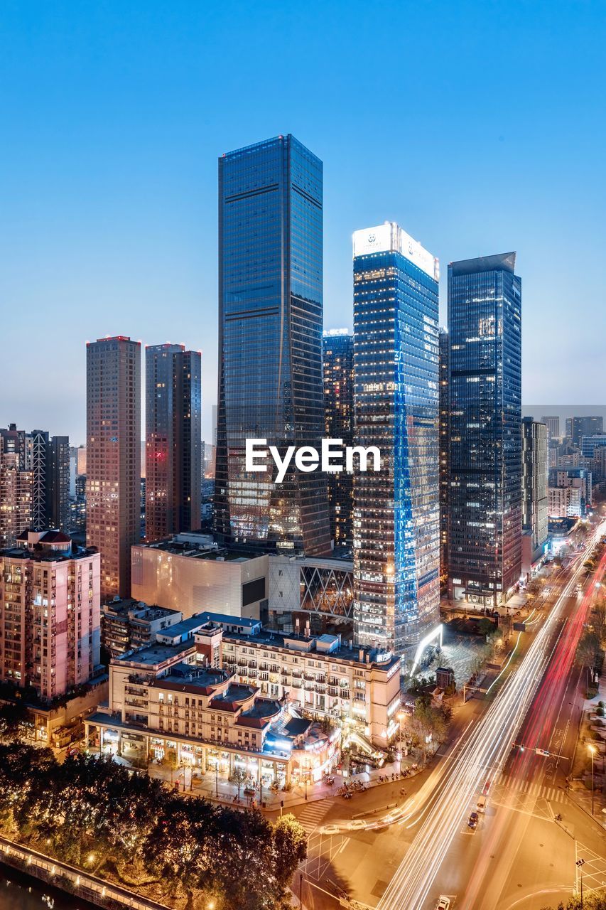 High angle view of illuminated cityscape against blue sky