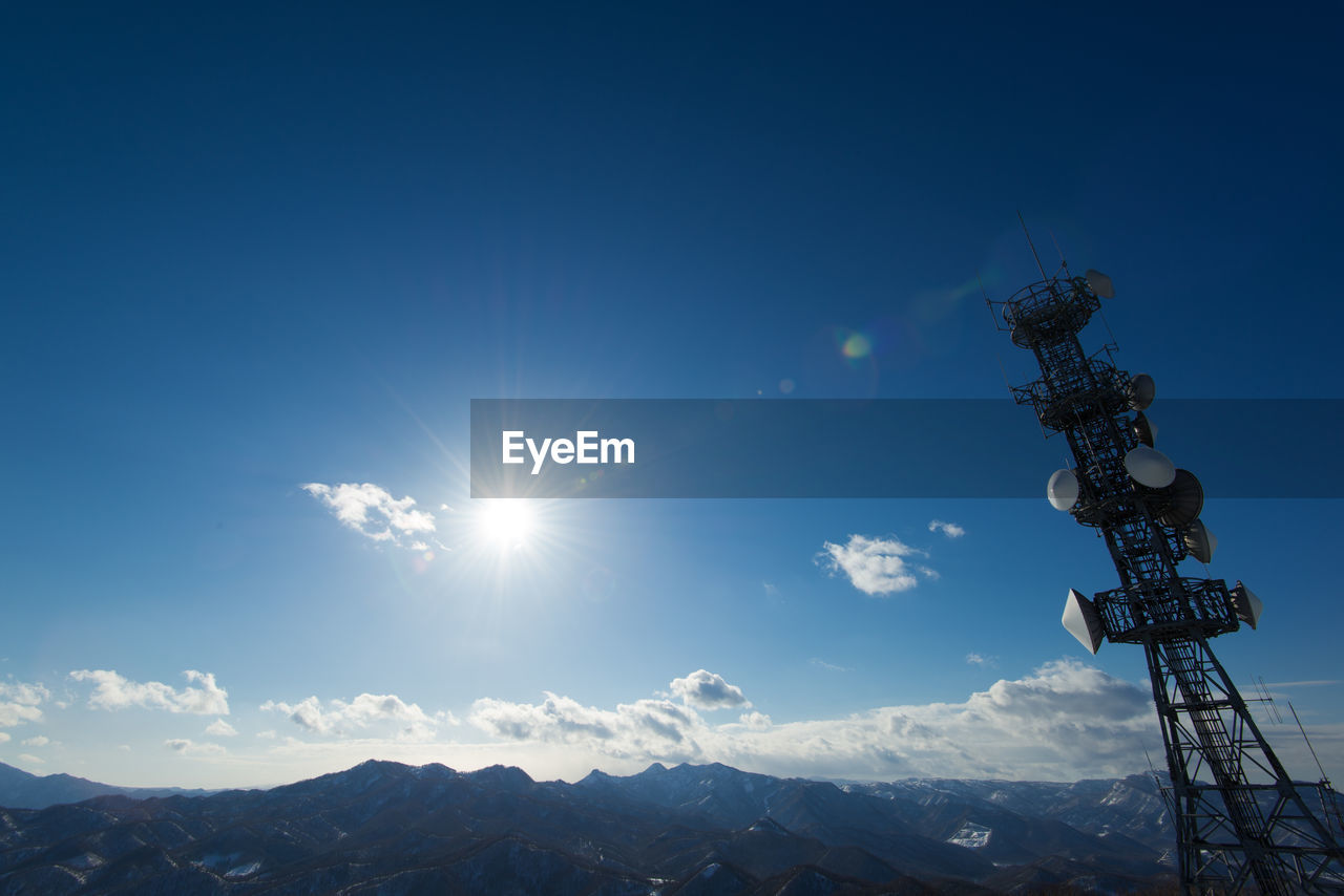 Low angle view of communications tower by mountain against sky