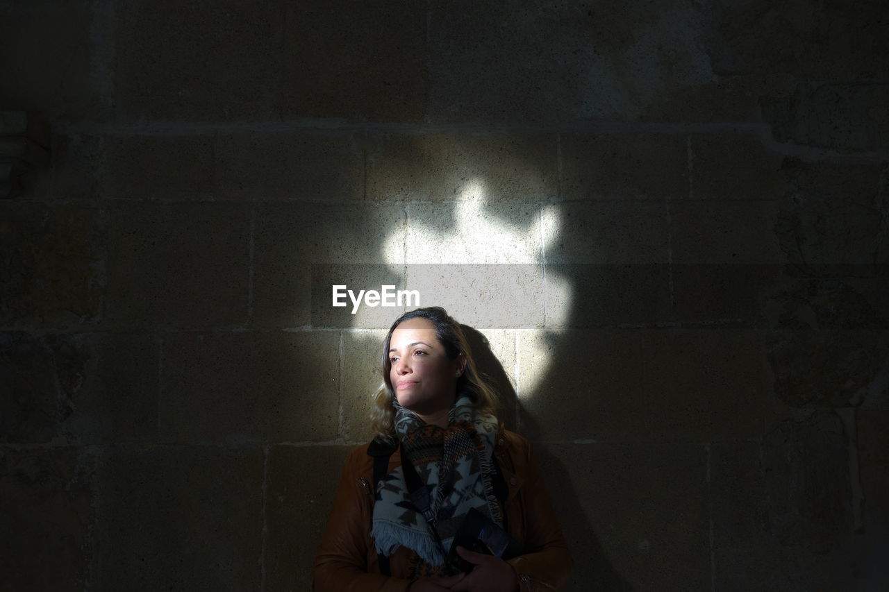 Sunlight falling on mid adult woman by wall