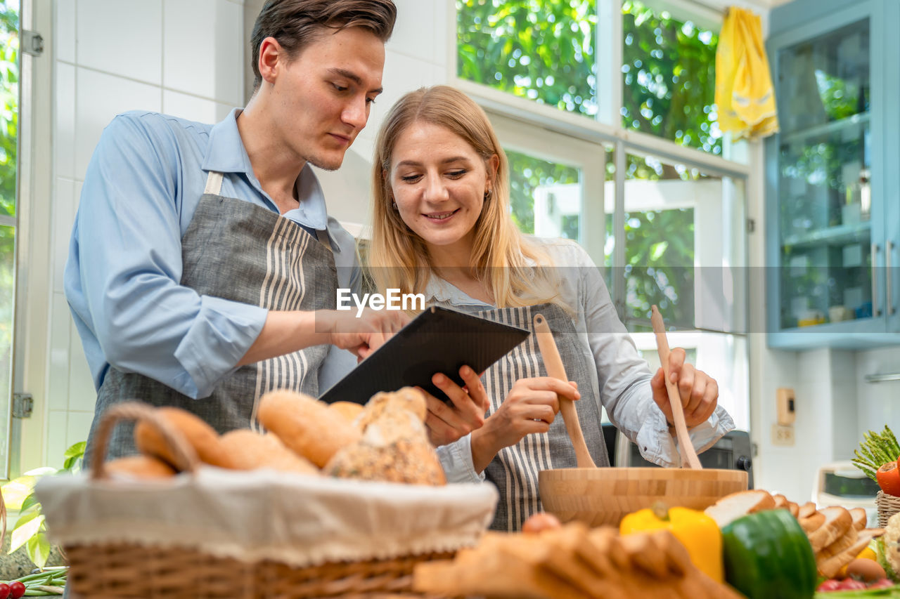 A woman and a man who are lovers are happy to help each other bake.