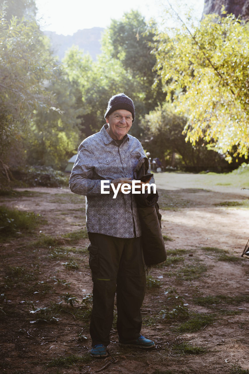 Portrait of smiling man standing on field in forest