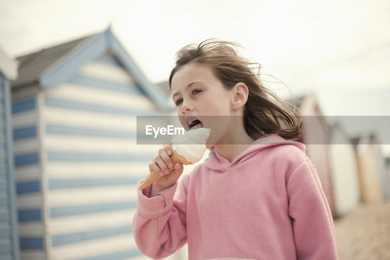 Girl licking ice cream cone at beach