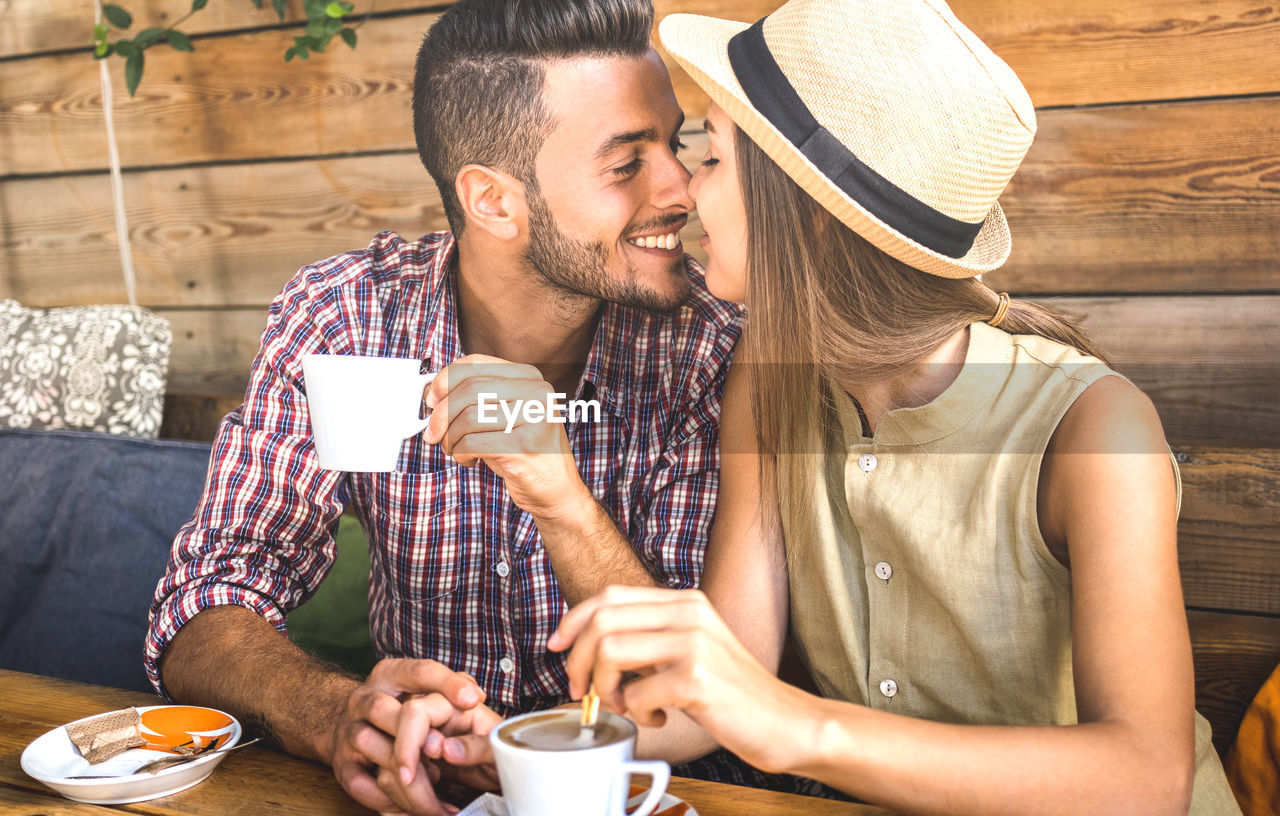 Young couple kissing while having coffee in cafe