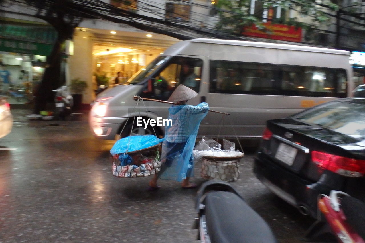 Vendor walking with carrying pole on road