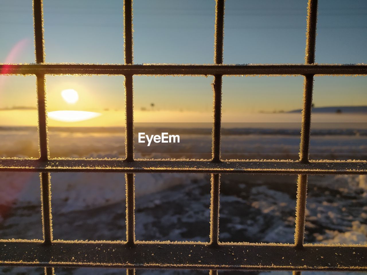 CLOSE-UP OF FENCE AGAINST SKY DURING SUNSET