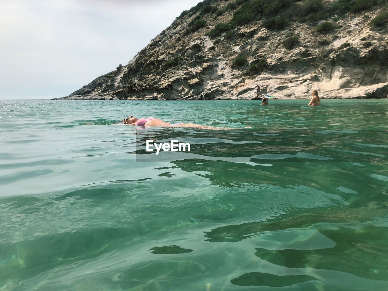 People swimming in sea against rocks