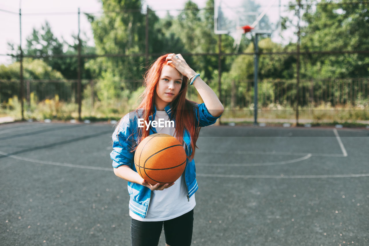 Portrait of a smiling teenage girl with a basketball on the sports field. sports, health, lifestyle