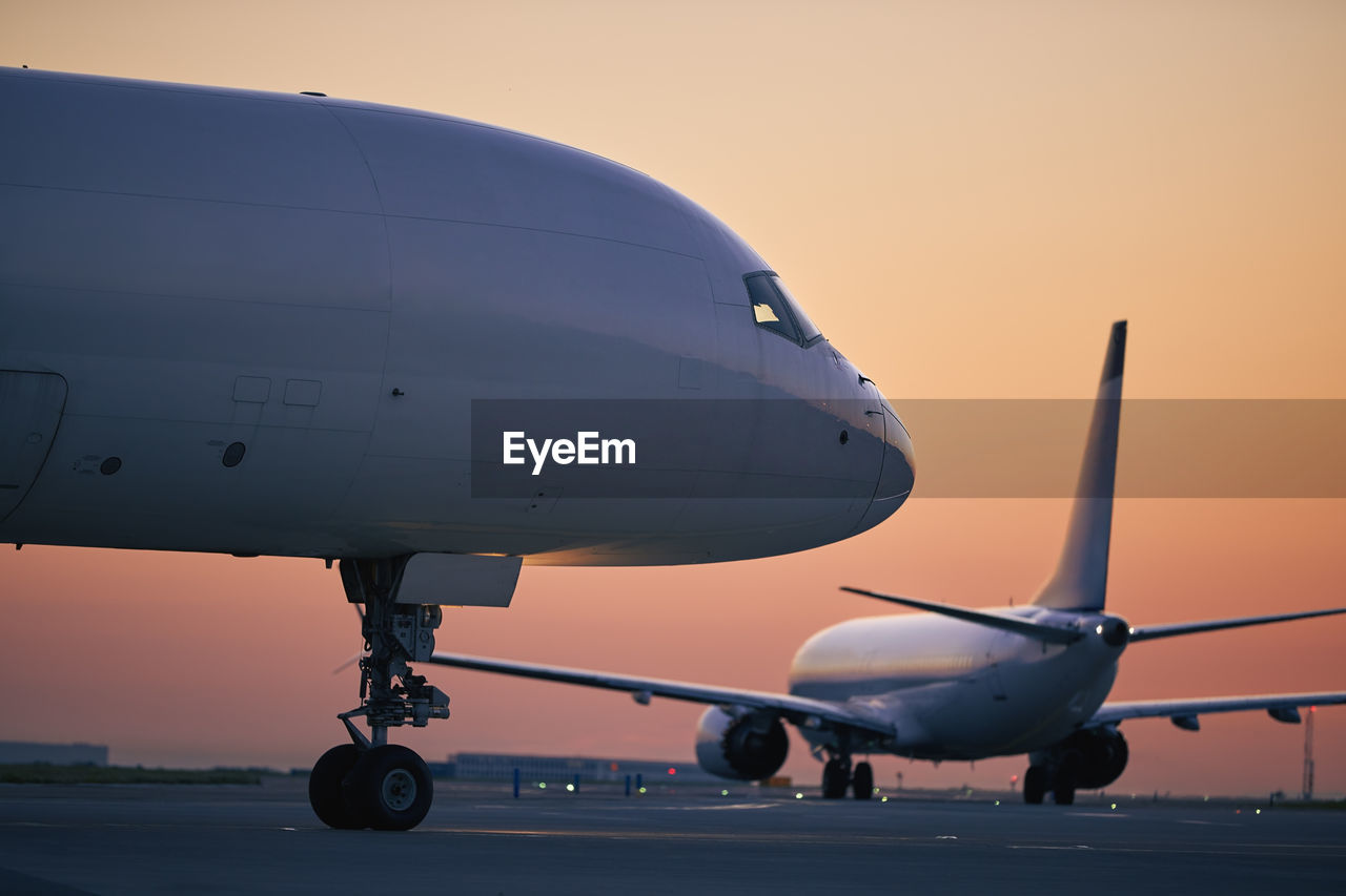 Cargo airplane is taxiing behind passenger airplane during morning busy traffic to airport runway.