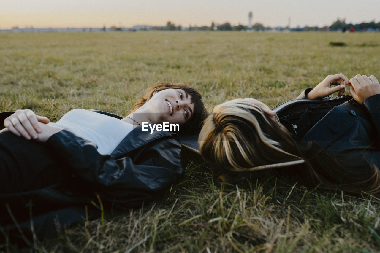 Young female friends lying down on grass in park