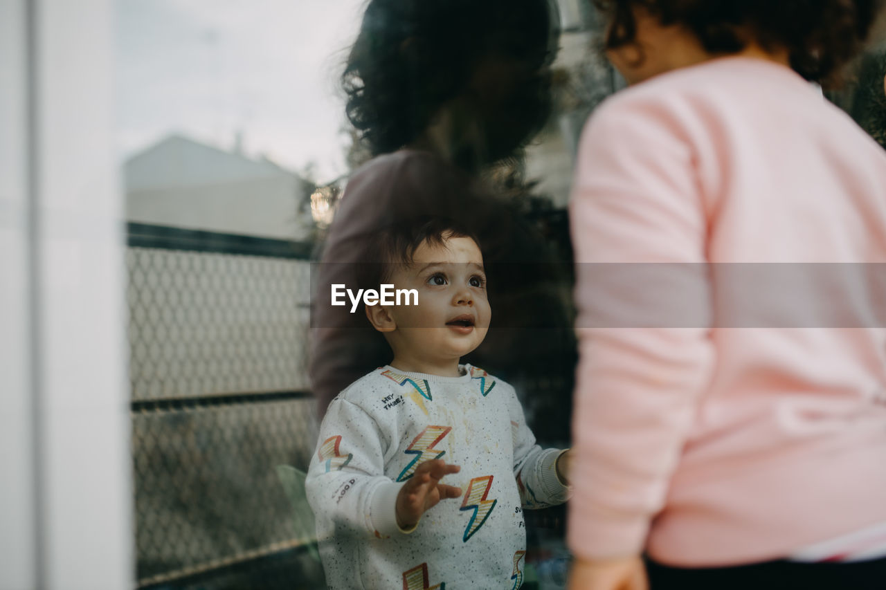 Brother looking at sister through window 