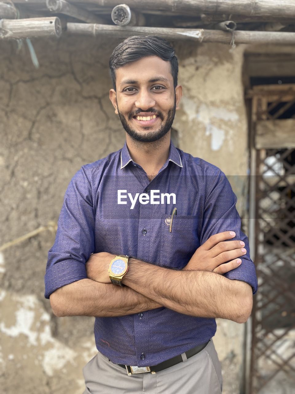 PORTRAIT OF A SMILING YOUNG MAN STANDING AGAINST WALL