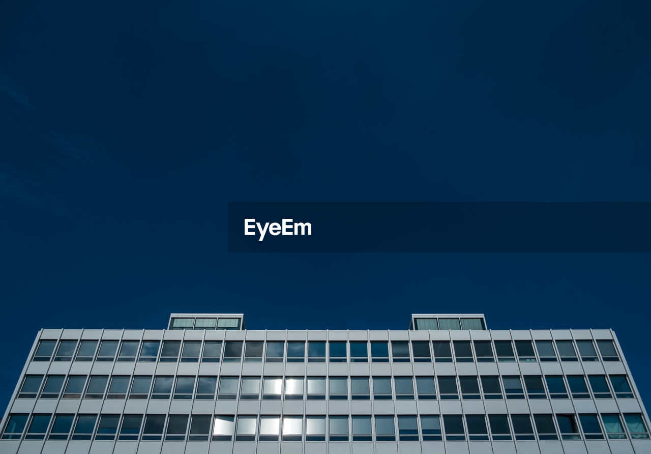 Low angle view of modern office building against clear blue sky