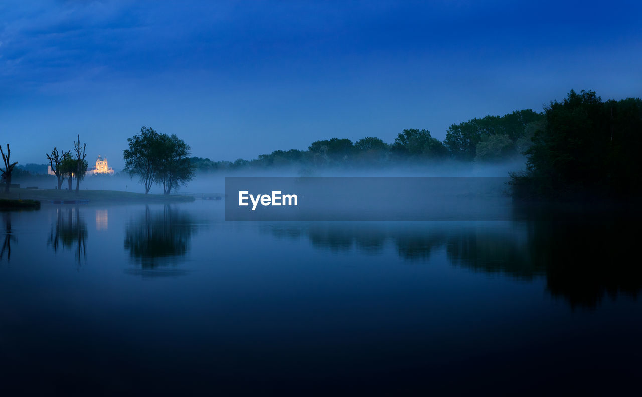 Reflection of trees in lake against blue sky