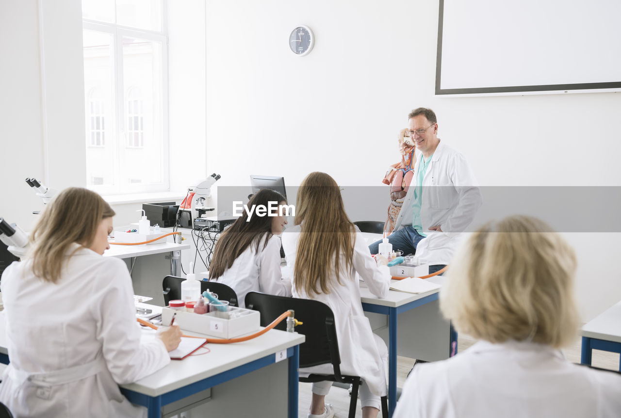 Students having lecture with professor in science lab classroom