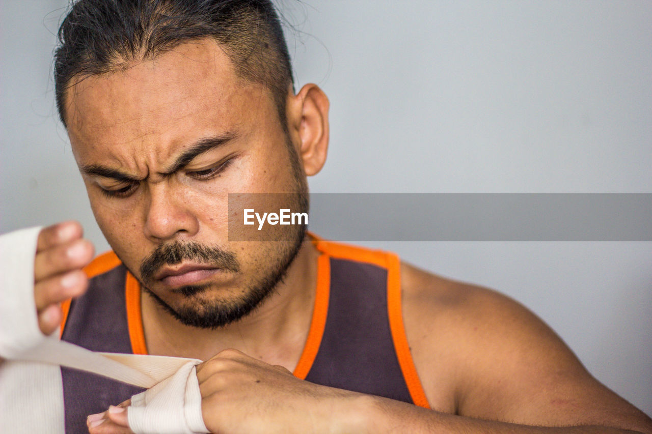 Close-up of man applying bandage against white background