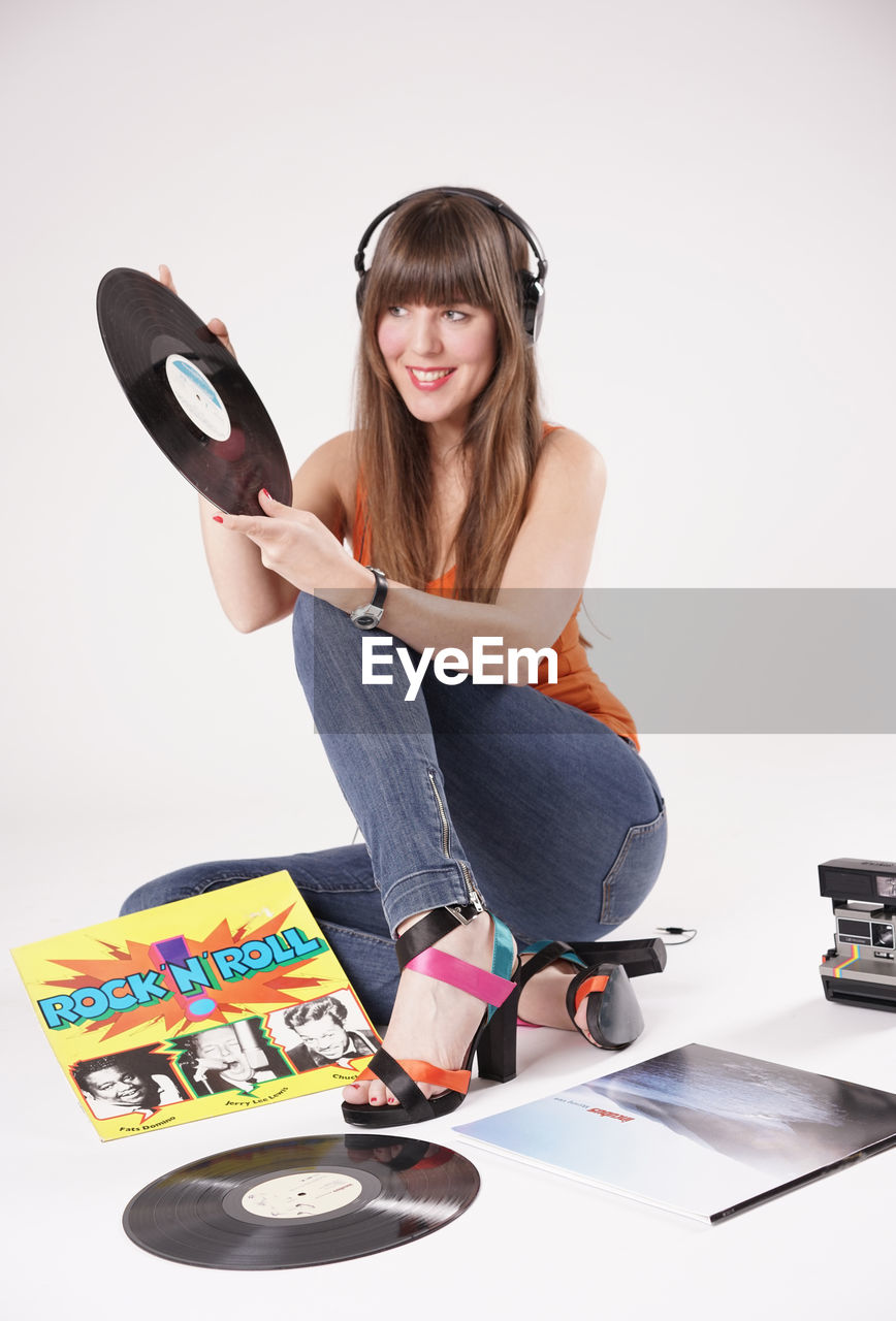 Smiling beautiful woman holding records against white background