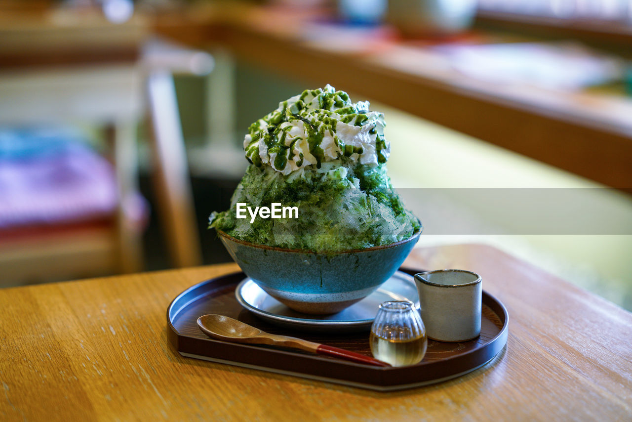 food and drink, food, green, table, matcha tea, indoors, focus on foreground, freshness, no people, drink, green tea, cup, wood, refreshment, sweet food, tea, dairy, sweet, close-up, dessert, culture, ice cream, healthy eating, produce, frozen food, hot drink, crockery, kitchen utensil