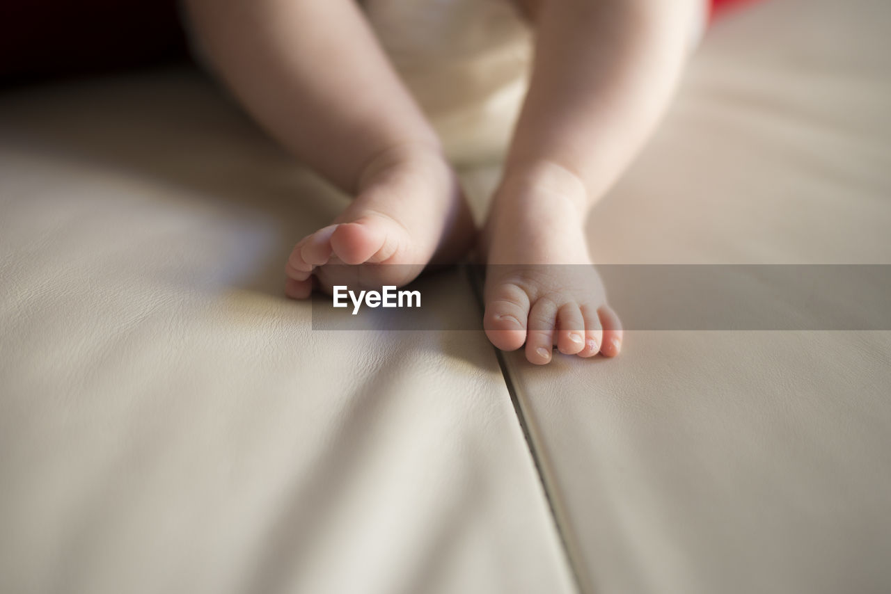 Low section of baby with bare feet on bed