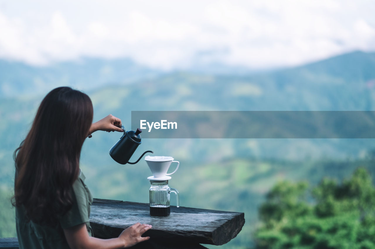 Woman drinking water from coffee in mountains