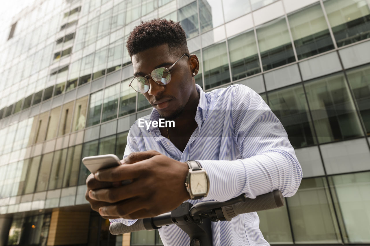 Young man using mobile phone in front of building