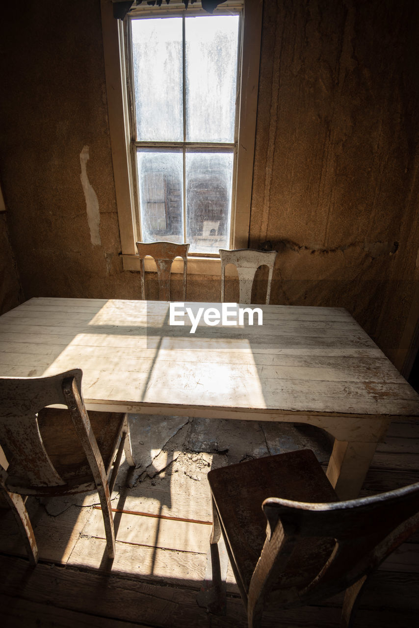 Empty chairs and table against window