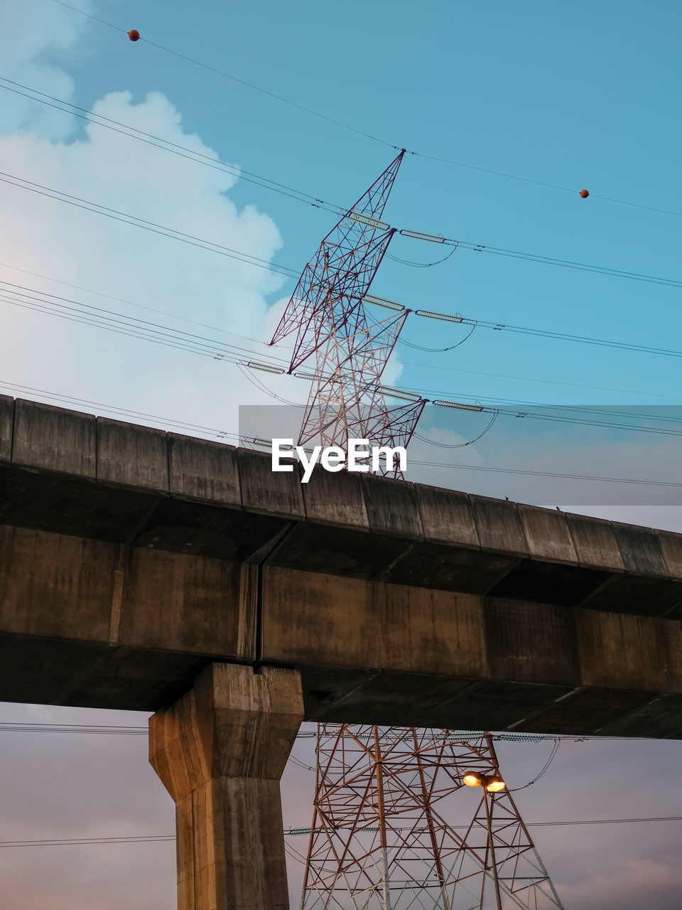 Low angle view of elevated train tracks with electricity power lines in the background