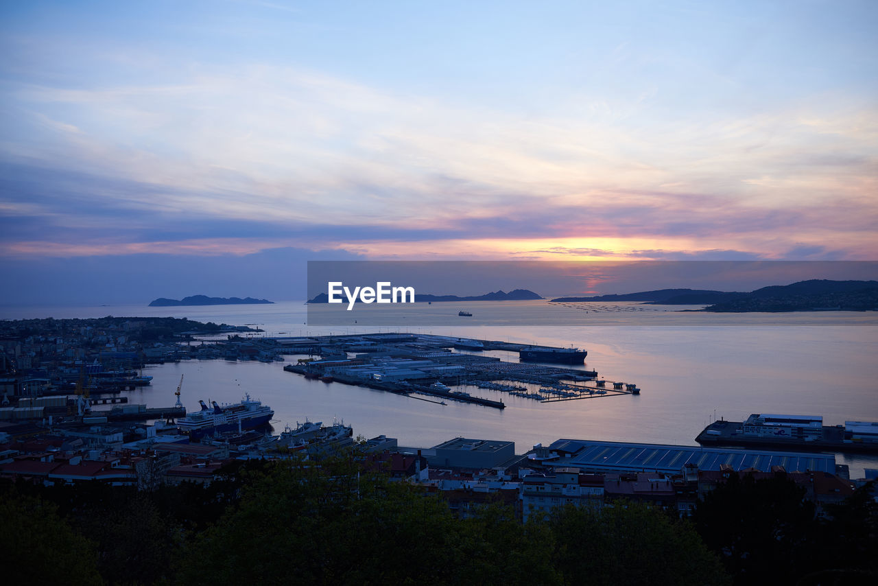 HIGH ANGLE VIEW OF SEA BY CITY BUILDINGS AGAINST SKY