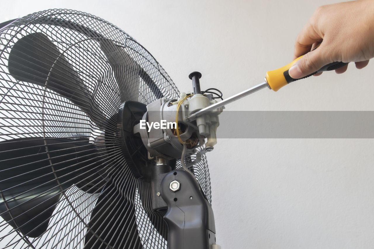 Cropped hand of man repairing electric fan at home