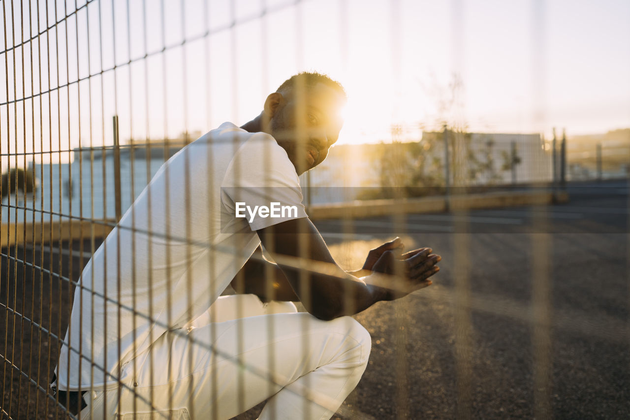 African man seen through fence during sunset
