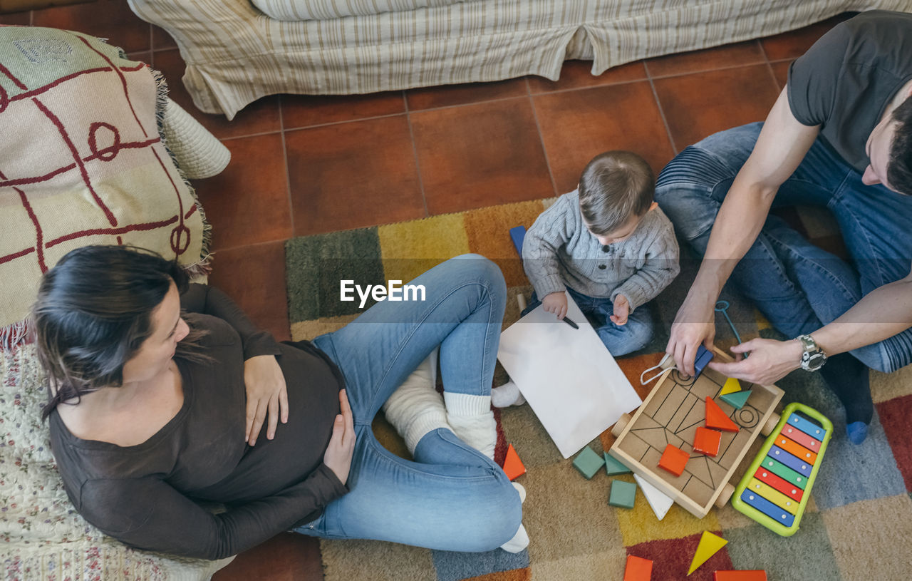 High angle view parents and son playing with toys at home