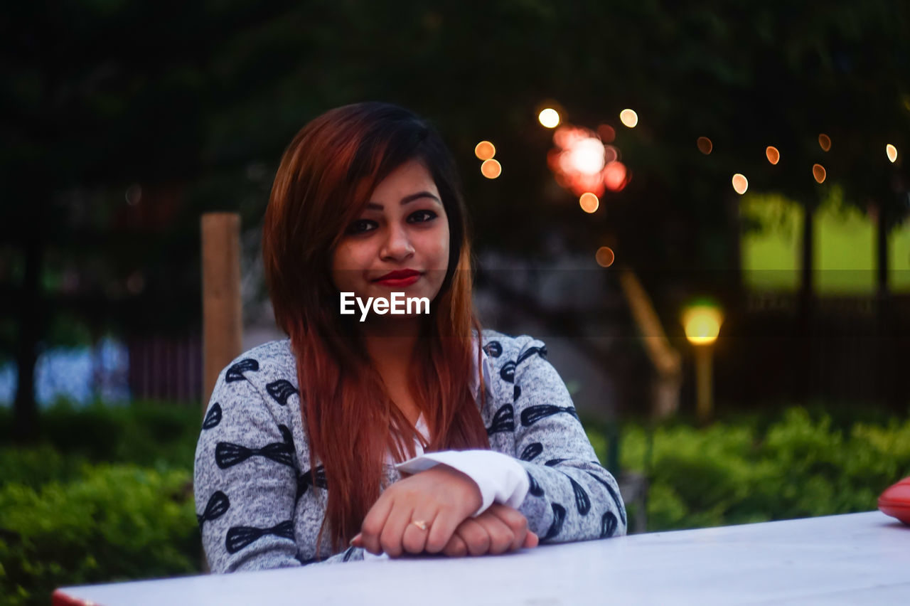 Portrait of young woman sitting at table in yard