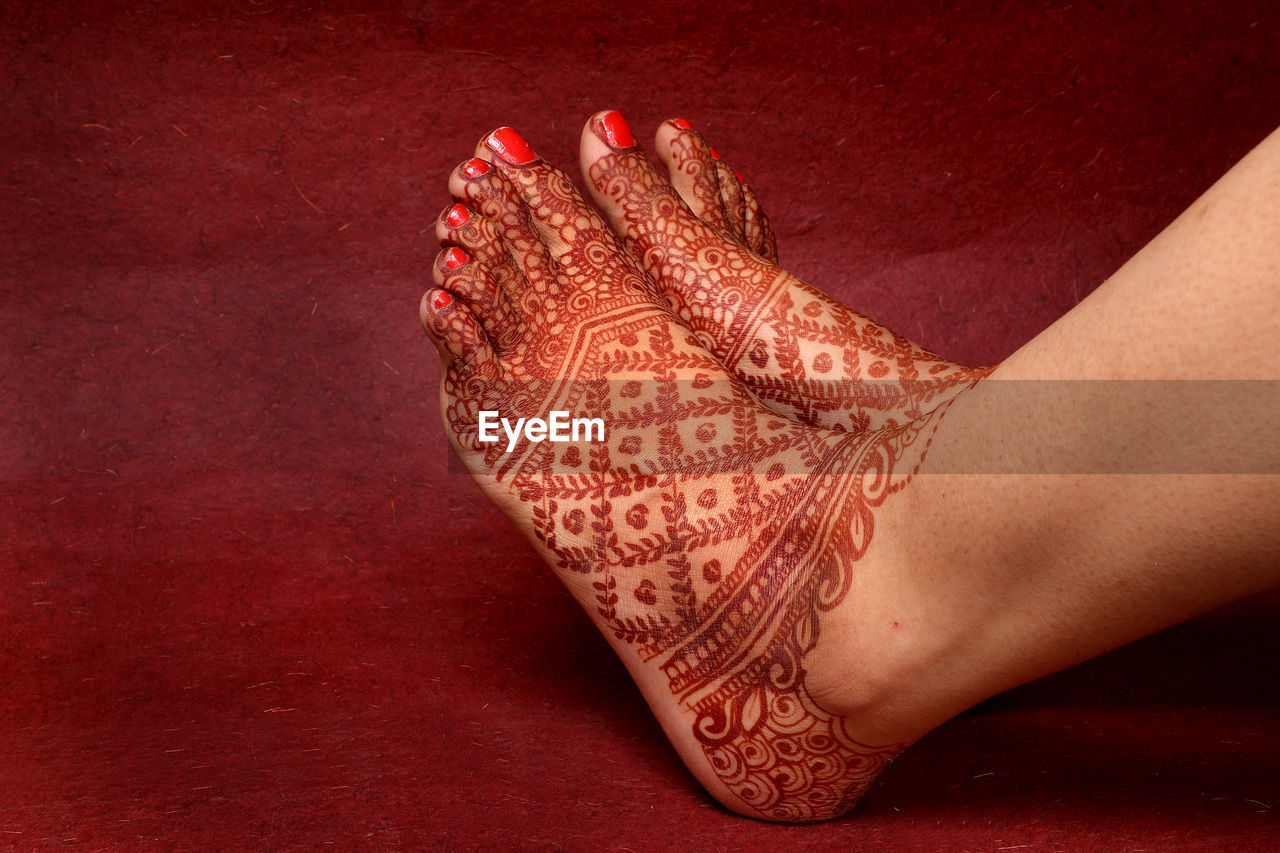 Lady hand feet with indian heena in indian wedding with red background