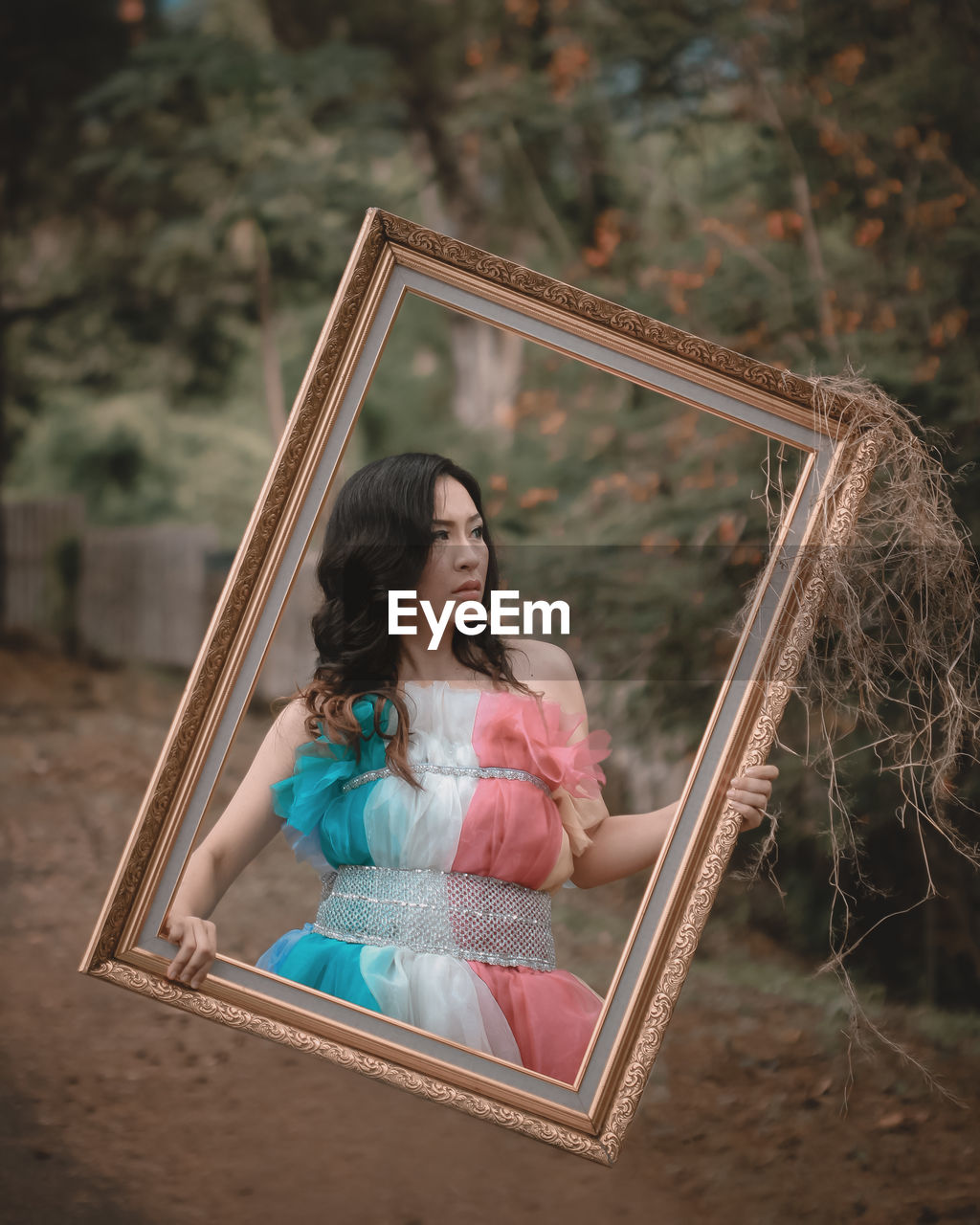 Digital composite image of woman looking away while holding picture frame 