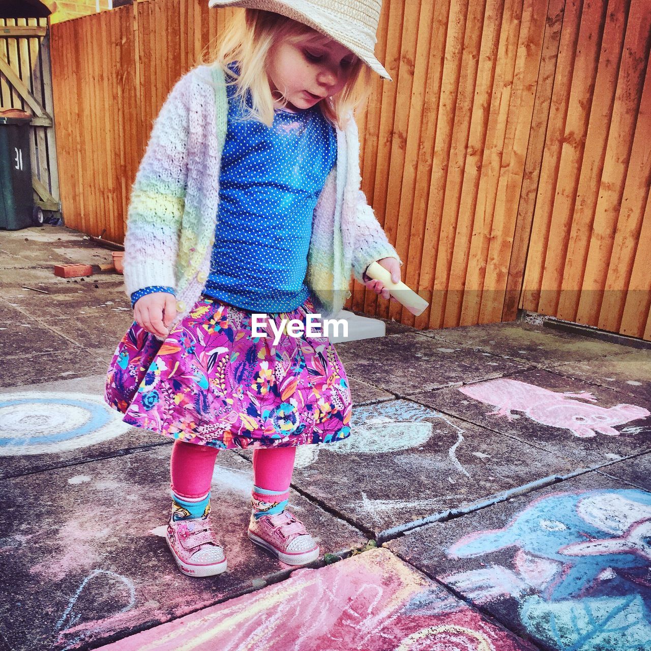 Cute girl doing chalk drawing on sidewalk