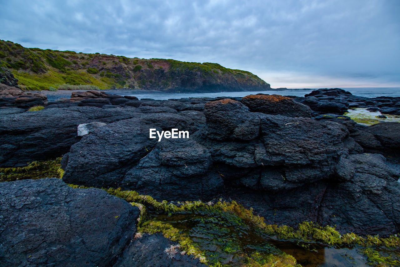 Scenic view of rocks on beach against sky