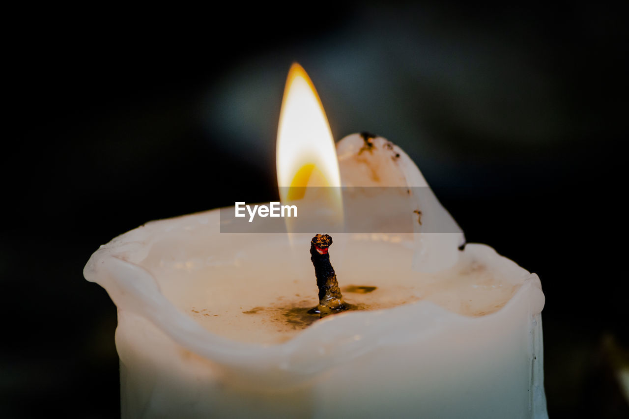 Close-up of lit candle against black background