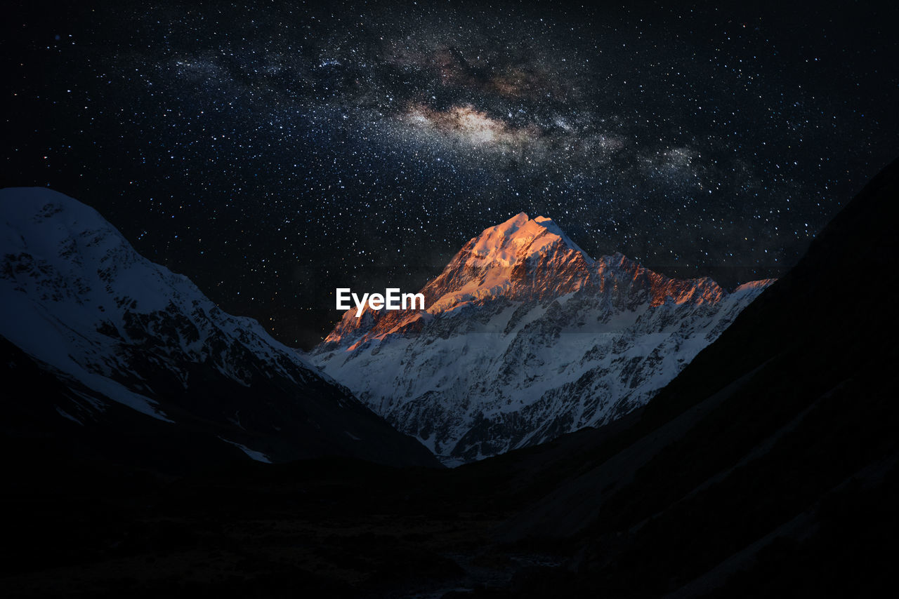 Scenic view of snowcapped mountains against star field