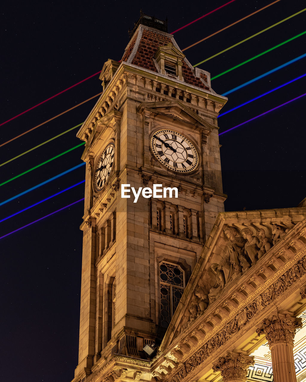 LOW ANGLE VIEW OF ILLUMINATED CLOCK TOWER AT NIGHT